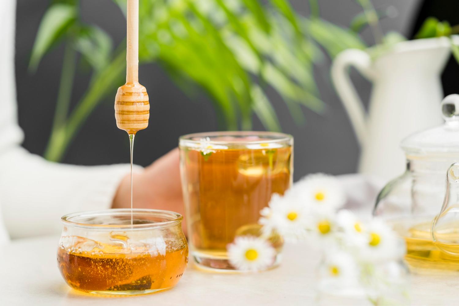 front-view-person-holding-glass-with-tea-honey-dipper